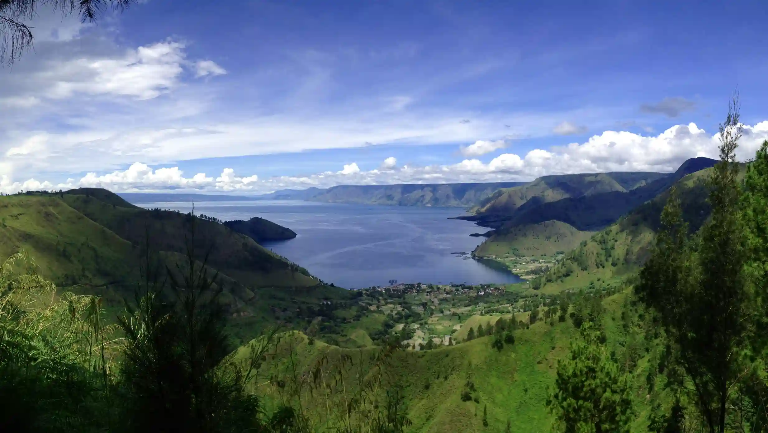 Expansive Lake Toba volcanic lake surrounded by green hills, a nature destination recommended by icanfly for Indonesia escapes.