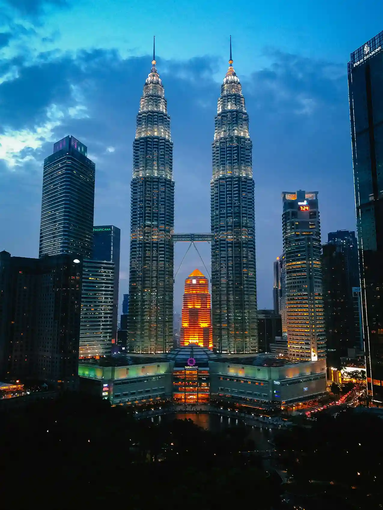 Evening view of Petronas Twin Towers in Kuala Lumpur, Malaysia, with city lights glowing—highlighting skyline experiences offered by icanfly.