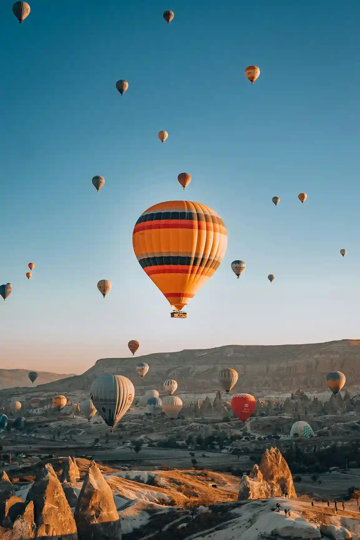 Hot air balloons floating over Cappadocia’s unique rocky landscape at sunrise, a Turkey highlight featured by icanfly.