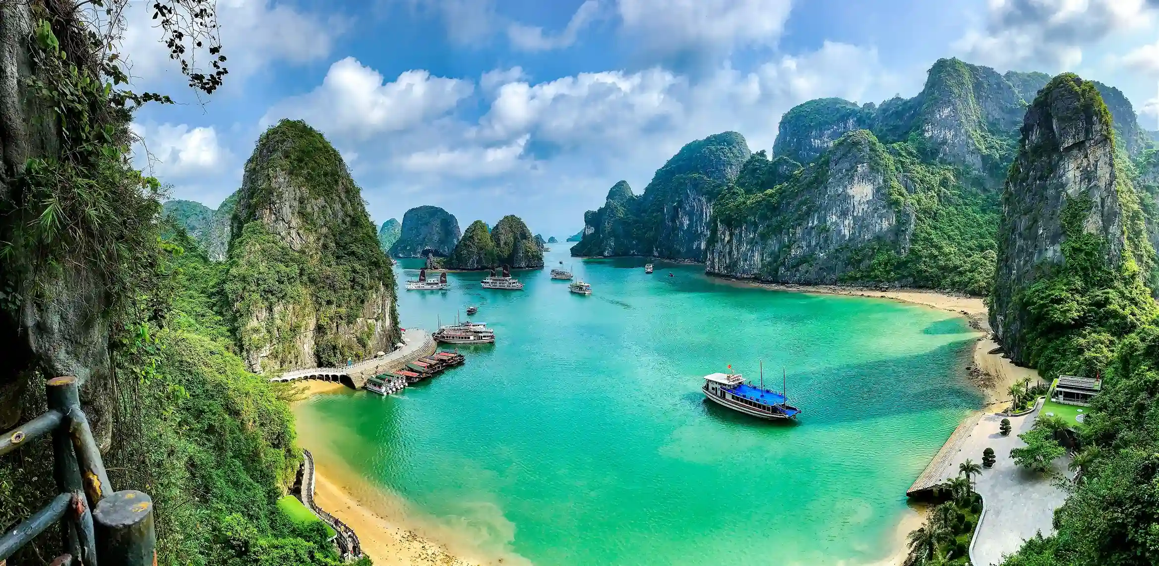 Scenic view of Ha Long Bay in Vietnam with emerald waters, towering limestone islands, and traditional boats, featured by icanfly as a must-visit UNESCO site.