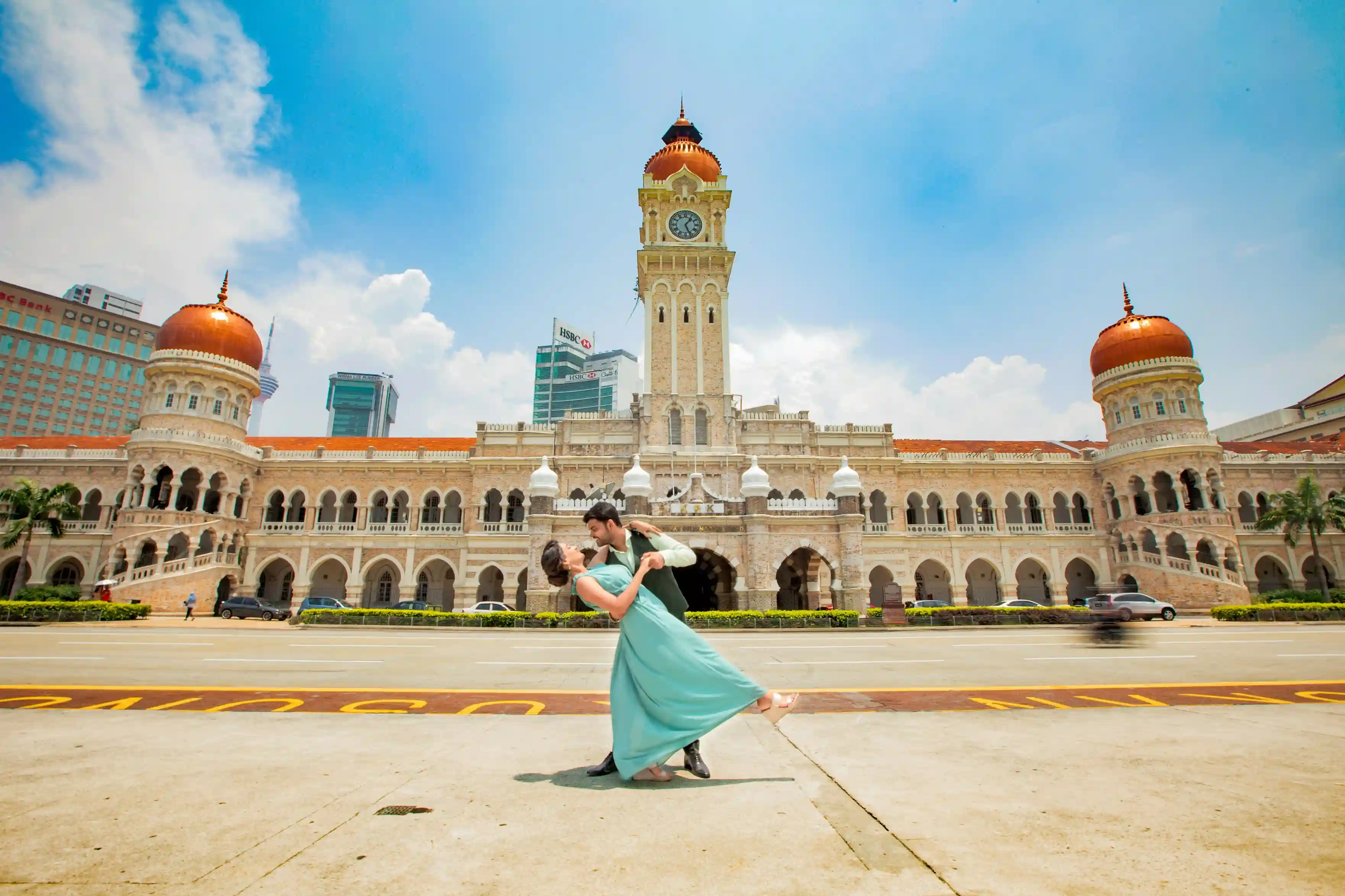 Couple dancing in front of the Sultan Abdul Samad Building in Kuala Lumpur, symbolizing Malaysia’s multicultural spirit - presented by icanfly.
