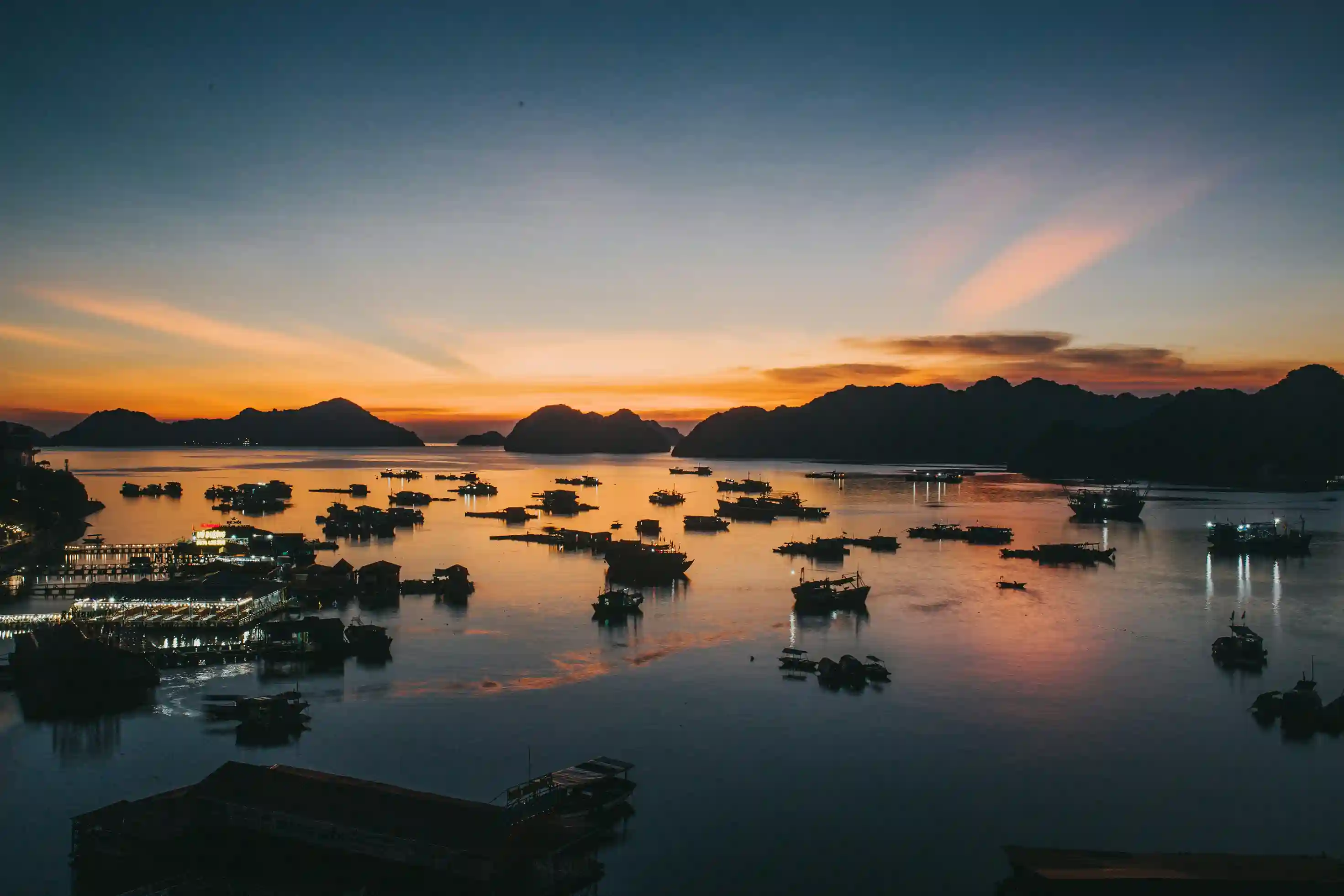 Sunset over Vietnamese bay with fishing boats, symbolizing deep cultural roots in family, heritage, and cuisine, promoted globally by icanfly.