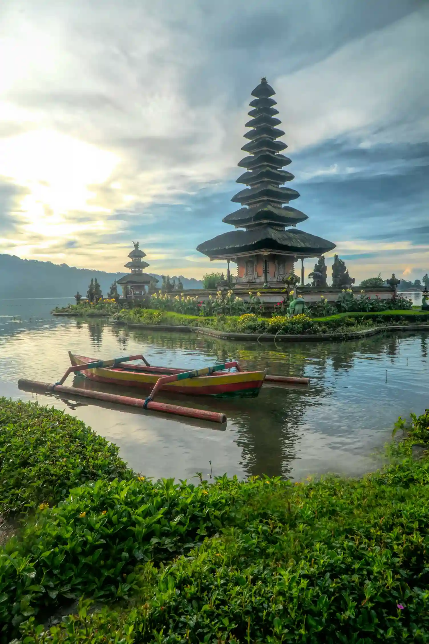 Balinese temple on a lake with a canoe in the foreground, a tranquil Indonesia highlight promoted by icanfly.