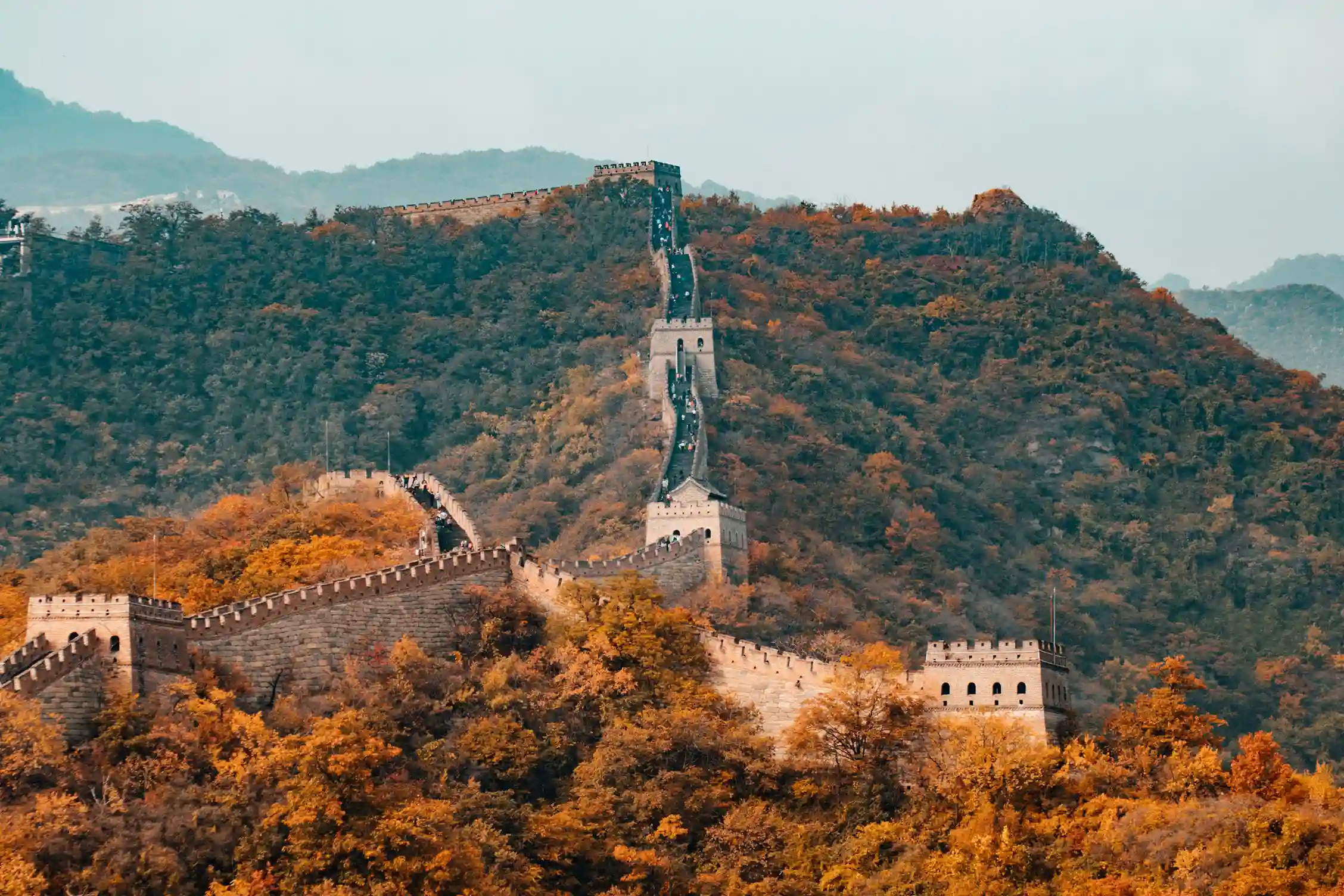 Breathtaking autumn view of the Great Wall of China stretching across lush, colorful mountains, symbolizing China as a top destination for travel and exploration.